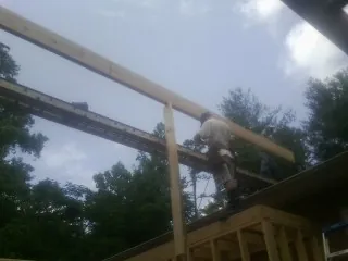 Carpenter setting a ridge beam over a new addition frame — Ice Dam Removal by Roofing Brothers in Kaleva