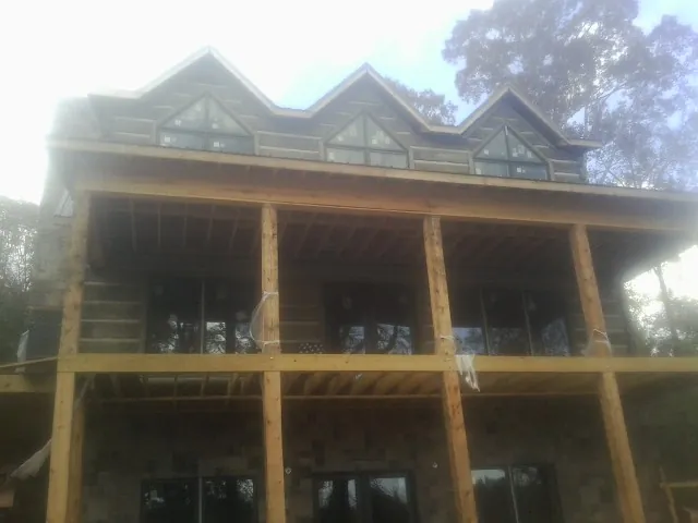 Dormers and porch framing on a large log home under construction — Roof Coating work by our crew in Kaleva