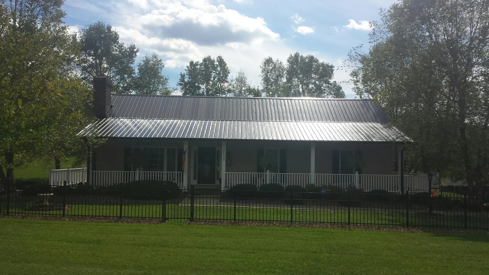 Gray metal roof on a brick ranch with a full width front porch — Gutter Guard Installation work by our crew in Kaleva