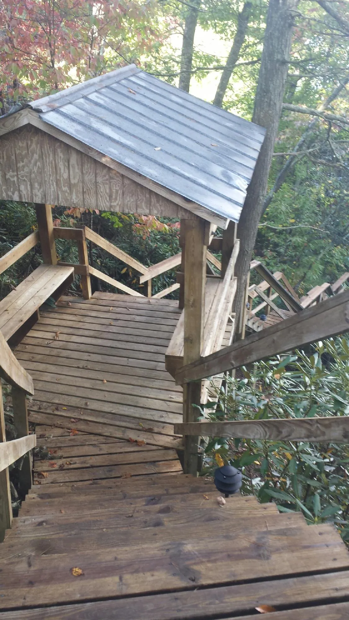 Metal roofed shelter over wooden steps on a wooded walkway — Skylight Repair & Installation work by our crew in Kaleva