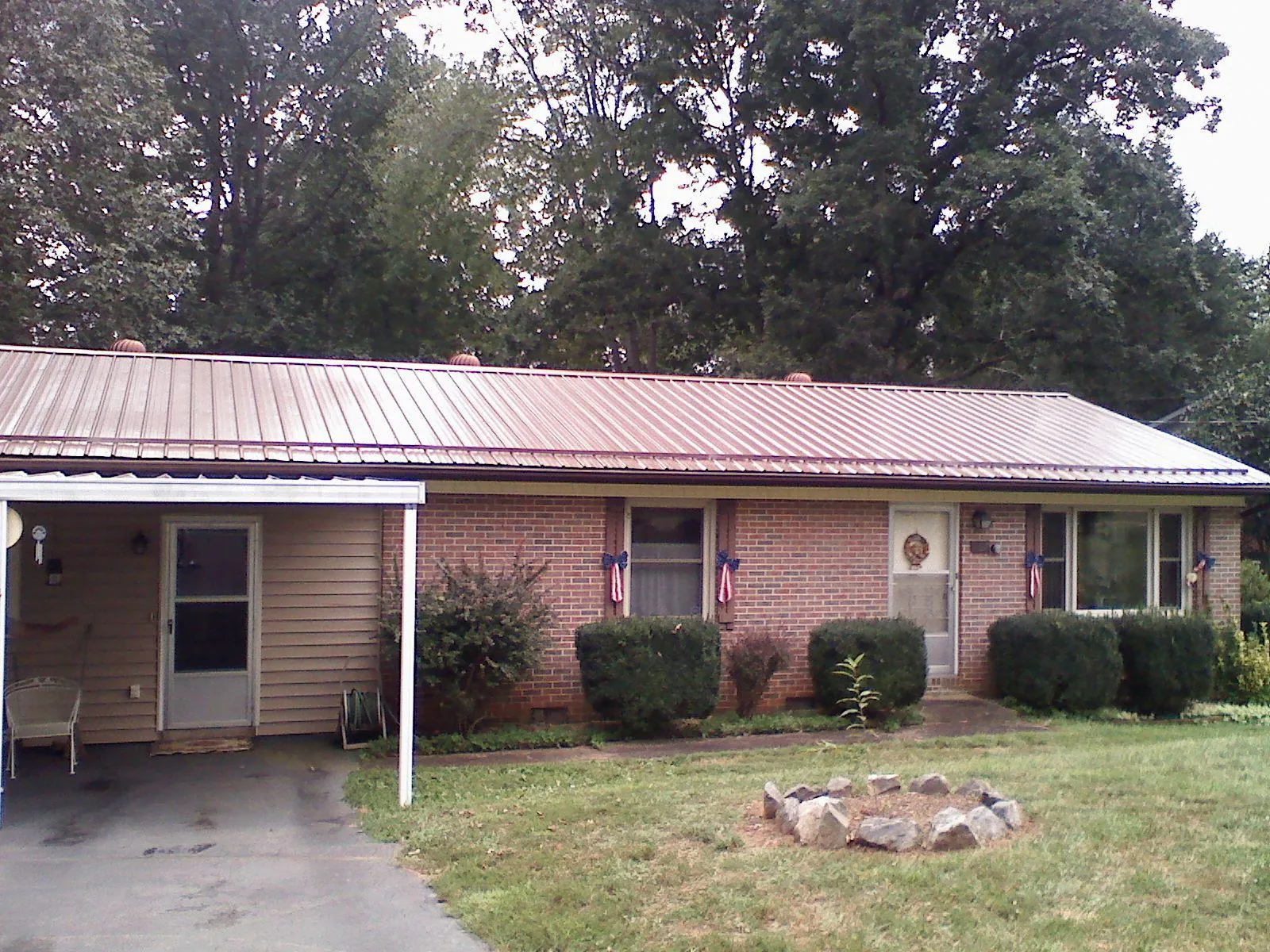 Bronze metal roof and carport on a brick ranch home — Roof Repair work by our crew in Kaleva